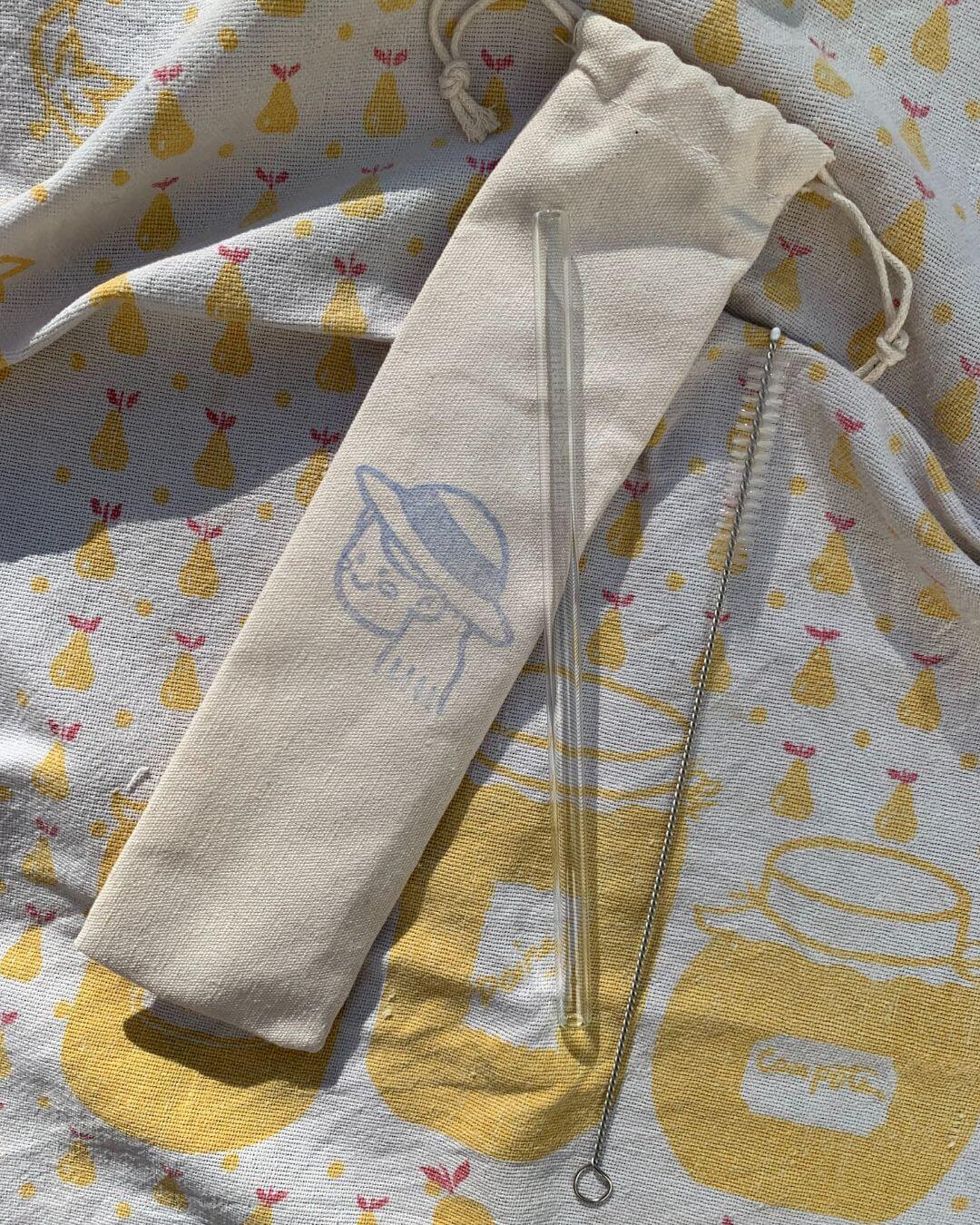 Paille en verre Maison Aimi dans sa pochette en lin et son goupillon